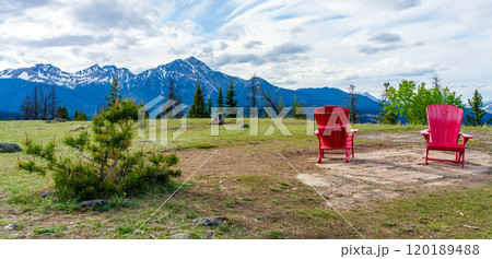 Red adirondack chairs on top of Old fort point trailhead. Jasper National Park nature scenery. Alberta, Canada. Forest and snow capped mountains in summer. Pyramid Mountain. Canadian Rockies. 120189488