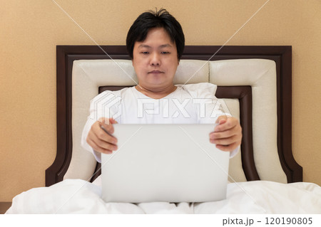 Work from home, a freelancer man leaning against the bed and using his laptop to work online on a bed. 120190805