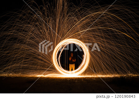 Spinning and burning Steel wool sparkle fire in the circle shape with long speed shutter shoot glowing light line to the ground. Spinning and burning Steel wool sparkle fire in the circle shape with long speed shutter shoot glowing light line to the ground. 120190843