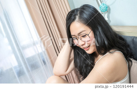 Asian Glasses Woman relax on her bed in the morning at her bedroom. 120191444