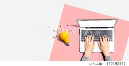 Person using a laptop computer and a light bulb 120192332