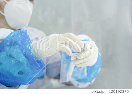 Close up to the rubber gloves on the asian medical staff is processing coronavirus or covid-19 test in the negative room pressure. Close up to the rubber gloves on the asian medical staff is processing coronavirus or covid-19 test in the negative room pressure. 120192370