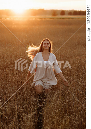A blonde woman runs through a field of tall grass at sunset. A blonde woman runs through a field of tall grass at sunset. 120194474