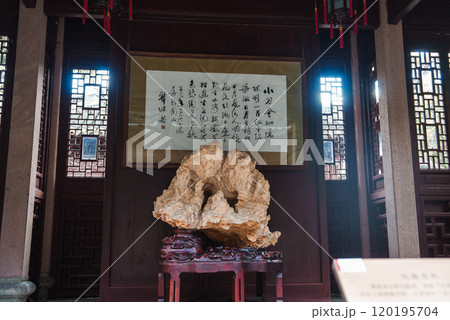 Interior scene in Shanghai featuring a rock sculpture on a wooden stand, framed Chinese calligraphy, lattice windows, and red lanterns. 120195704