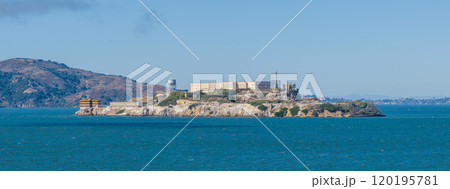 Alcatraz Island features the historic penitentiary and watchtower, surrounded by San Francisco Bay's blue waters and Marin Headlands in the background. 120195781