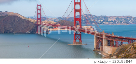 The Golden Gate Bridge's International Orange color contrasts with blue waters and Marin County hills, capturing its iconic structure on a clear day. 120195844