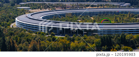 The image captures an aerial view of Apple Park in Cupertino, California, featuring its circular design, solar panels, and a rainbow arch in the courtyard. 120195983