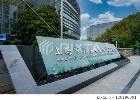 The image shows the Bureau of Exit Entry Administration in Shanghai, China, featuring a glass and steel building, lush greenery, and a clear blue sky. The image shows the Bureau of Exit Entry Administration in Shanghai, China, featuring a glass and steel building, lush greenery, and a clear blue sky. 120196001