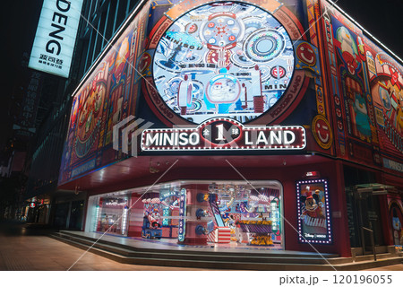 The Miniso Land storefront in Shanghai features colorful graphics and cartoon characters, illuminated by neon lights, set in a bustling urban environment. 120196055