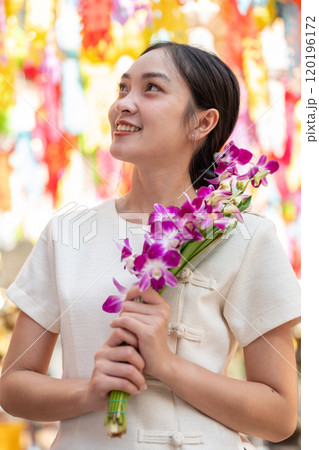 A charming Asian woman admires the beautiful, colorful lanterns in a temple in Chiang Mai, Thailand. 120196172
