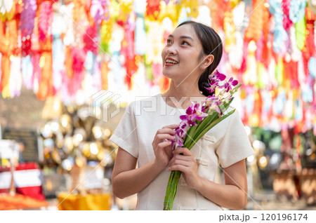 A charming Asian woman admires the beautiful, colorful lanterns in a temple in Chiang Mai, Thailand. 120196174