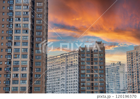 High rise residential buildings in Shanghai under a dramatic sunset sky, featuring modern architecture with numerous windows and balconies. 120196370