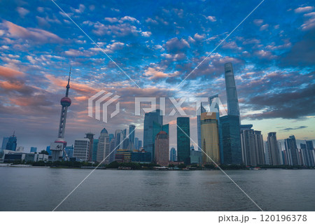 The iconic skyline of Shanghai features the Oriental Pearl Tower and Shanghai Tower, set against a vibrant sky with the Huangpu River in the foreground. 120196378