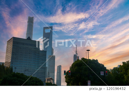 View of Shanghai's skyline at sunset, featuring the Shanghai World Financial Center and Shanghai Tower, with greenery and traffic lights in the foreground. View of Shanghai's skyline at sunset, featuring the Shanghai World Financial Center and Shanghai Tower, with greenery and traffic lights in the foreground. 120196432