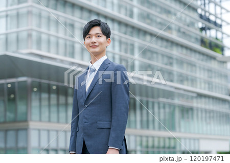 オフィスビルの前で微笑む若いビジネスマン 120197471