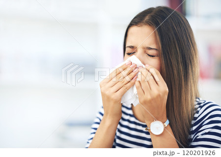 Its that time of the year again. Shot of a young woman with allergies sneezing into a tissue at home. Its that time of the year again. Shot of a young woman with allergies sneezing into a tissue at home. 120201926