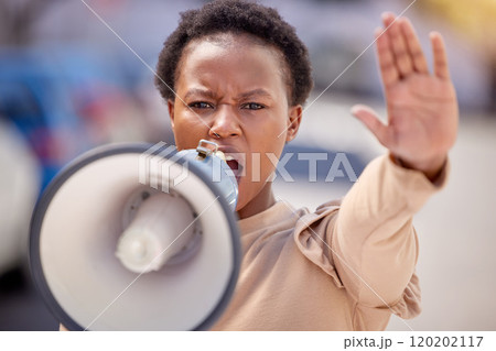 Fight for what you believe in. Shot of a young woman with her hand raised speaking through a megaphone at a protest. Fight for what you believe in. Shot of a young woman with her hand raised speaking through a megaphone at a protest. 120202117
