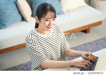 パソコン画面を見る若い女性　リビング　ワンルーム 120204033