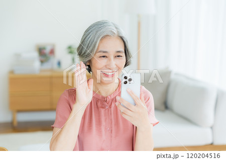 リビングでスマホを操作するシニア女性 120204516