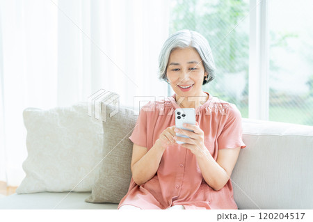 リビングでスマホを操作するシニア女性 リビングでスマホを操作するシニア女性 120204517