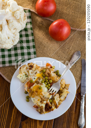 fried omelette with cauliflower and vegetables in a plate on a wooden table 120205090