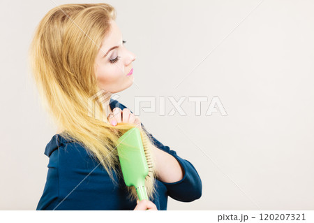 Woman brushing her long blonde hair 120207321