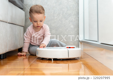 Little girl holds robot vacuum cleaner with her hand. Concept of communication with smart devices 120207995