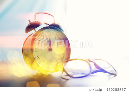 Background with a clock on the table and bokeh in pastel rainbow colors. Time for rest and travel. 120208887