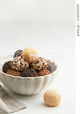 Typical Brazilian sweet brigadeiro. A heap of assorted flavors of candies on a white table with copy space 120209385