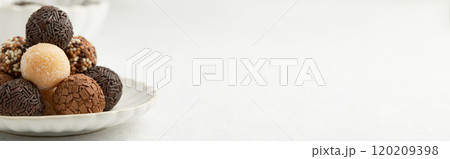 Typical Brazilian sweet brigadeiro. A heap of assorted flavors of candies on a white table Typical Brazilian sweet brigadeiro. A heap of assorted flavors of candies on a white table 120209398