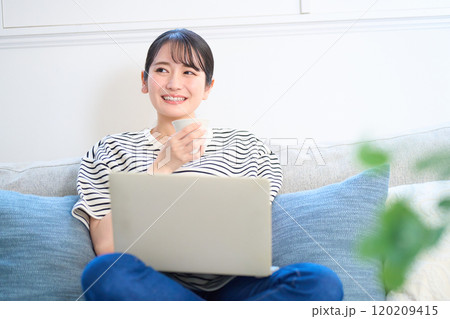 パソコン画面を見る若い女性　リビング　ワンルーム 120209415