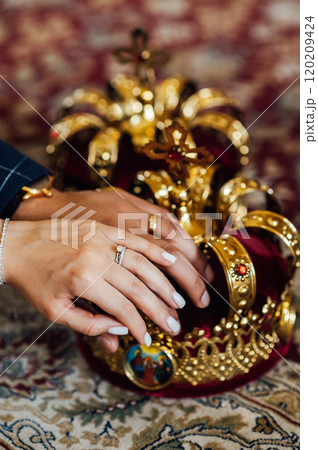 two wedding crowns in the church. The hands of the newlyweds lie on the crown two wedding crowns in the church. The hands of the newlyweds lie on the crown 120209424