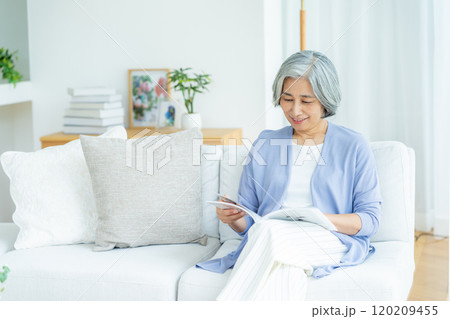 リビングで読書するシニア女性 120209455