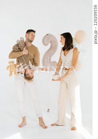 Happy family with their son celebrates his two year anniversary with a cake and balloons 120209556