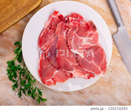 Slices of raw pork loin head on plate with parsley Slices of raw pork loin head on plate with parsley 120210265