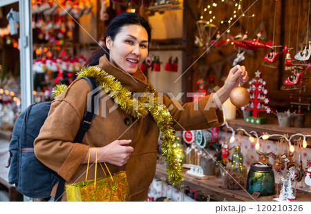 Portrait of smiling happy woman holding christmas ball in her hands on street market 120210326
