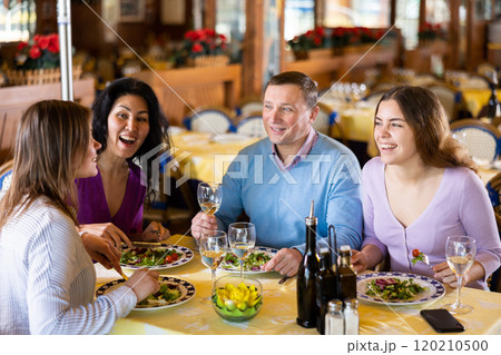 Group of friends enjoying evening meal at restaurant Group of friends enjoying evening meal at restaurant 120210500