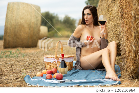 Woman sitting in robe with wine during picnic 120210964