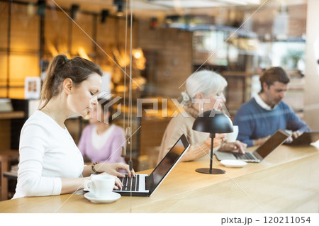 Middle-aged woman sitting at table, using laptop and enjoing cup of tea in coffee house. Modern female lifestyle concept Middle-aged woman sitting at table, using laptop and enjoing cup of tea in coffee house. Modern female lifestyle concept 120211054