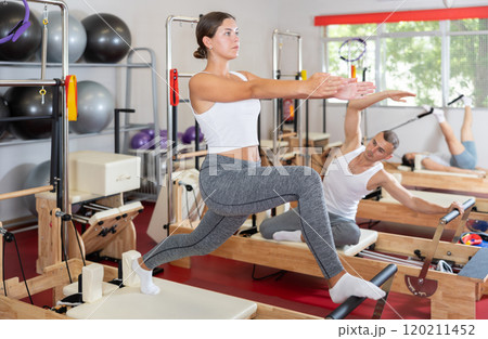 Young woman doing stretching on pilates reformer Young woman doing stretching on pilates reformer 120211452