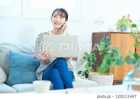電話をする若い女性 リビング ワンルーム 電話をする若い女性 リビング ワンルーム 120211467