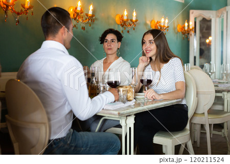 Group of satisfied friends enjoying evening meal at restaurant 120211524