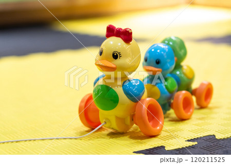 Pull-along duck toy for toddlers on yellow mat. Concept of fun and engaging playtime for kids Pull-along duck toy for toddlers on yellow mat. Concept of fun and engaging playtime for kids 120211525