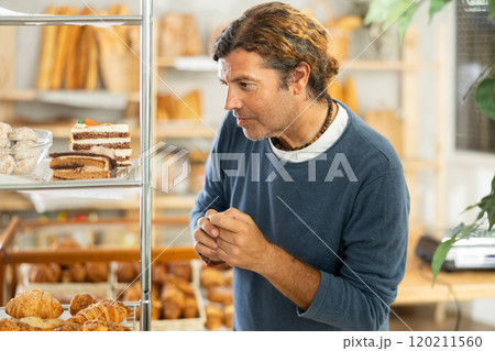 Middle-aged man chooses pastry in bakery 120211560