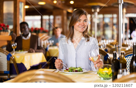Smiling young woman having dinner in cozy restaurant 120211607