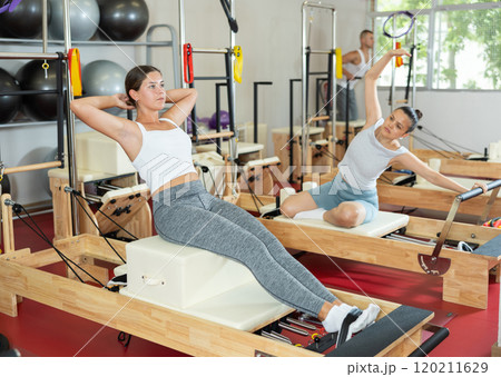 Young woman training her abs on pilates machine 120211629