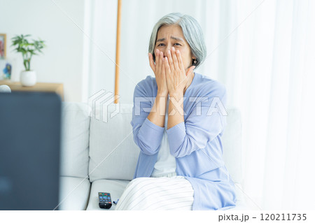 リビングでテレビを見るシニア女性 120211735