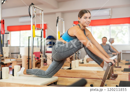 Girl performs exercise on reformer to improve coordination, balance, and posture 120211855