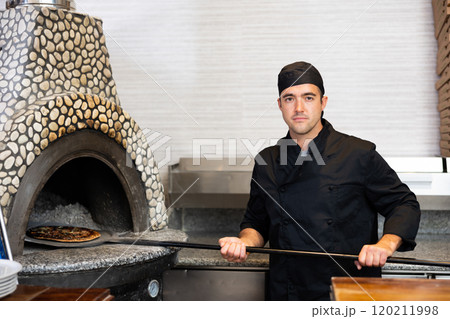 Skilled man chef preparing pizza in restaurant 120211998