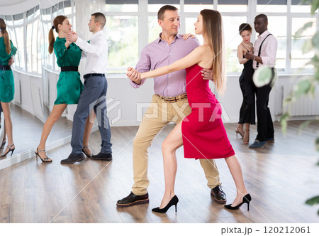 Dance studio - group of beautifully dressed people learn to dance tango Dance studio - group of beautifully dressed people learn to dance tango 120212061